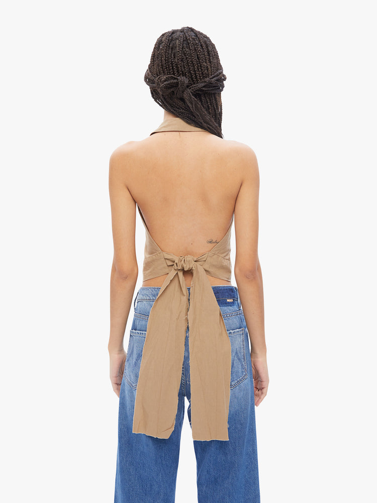 Back view of a woman in Elsa Esturgie a french brand that uses natural fabrics and responsible practices to create minimalist timeless pieces, handcrafted from 100% organic cotton in a camel hue, the sleeveless Idole top is designed with a Vneck, notched collar, 3 button placket and an extra wide cropped hem
