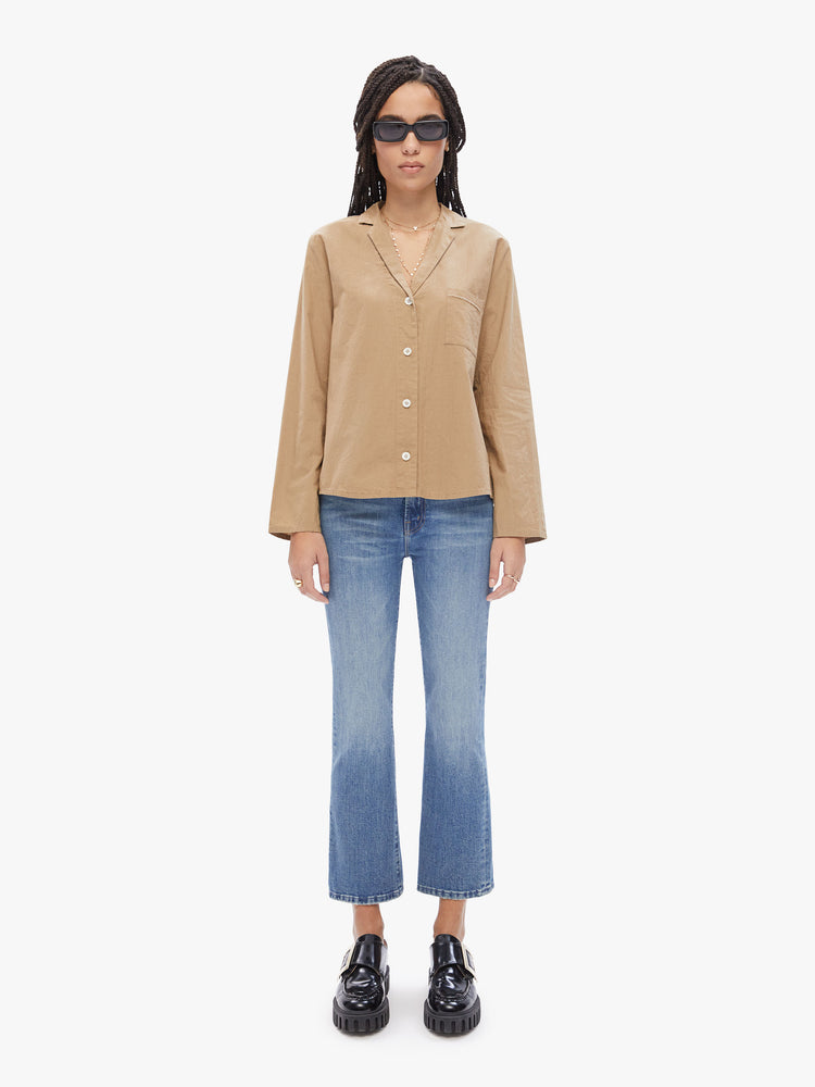 Full body view of a woman in a French brand Elsa Esturgie , this long sleeve top is designed with a vneck, notched collar, buttons down the front and long sleeves made from 100% Organic cotton in a camel hue
