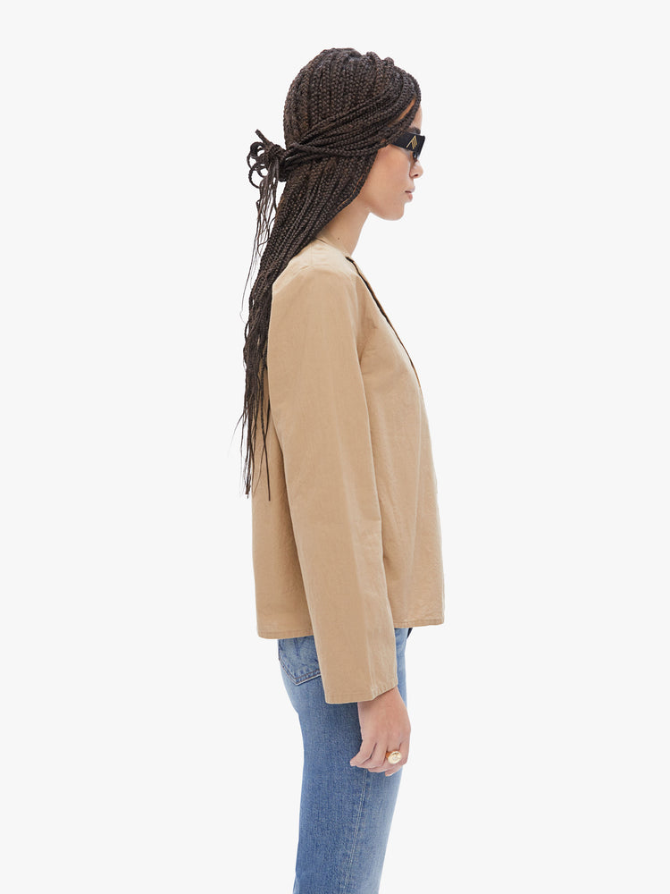 Side view of a woman in a French brand Elsa Esturgie , this long sleeve top is designed with a vneck, notched collar, buttons down the front and long sleeves made from 100% Organic cotton in a camel hue