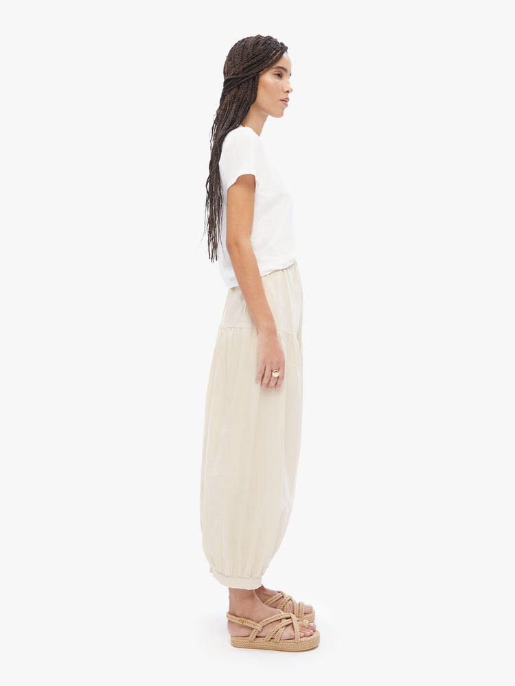 Side view of a woman in Elsa Esturgie a French brand, these wide-leg balloon pants have a gathered waistband, side pockets, elastic hems and voluminous fit in a 100% organic cotton cream hue
