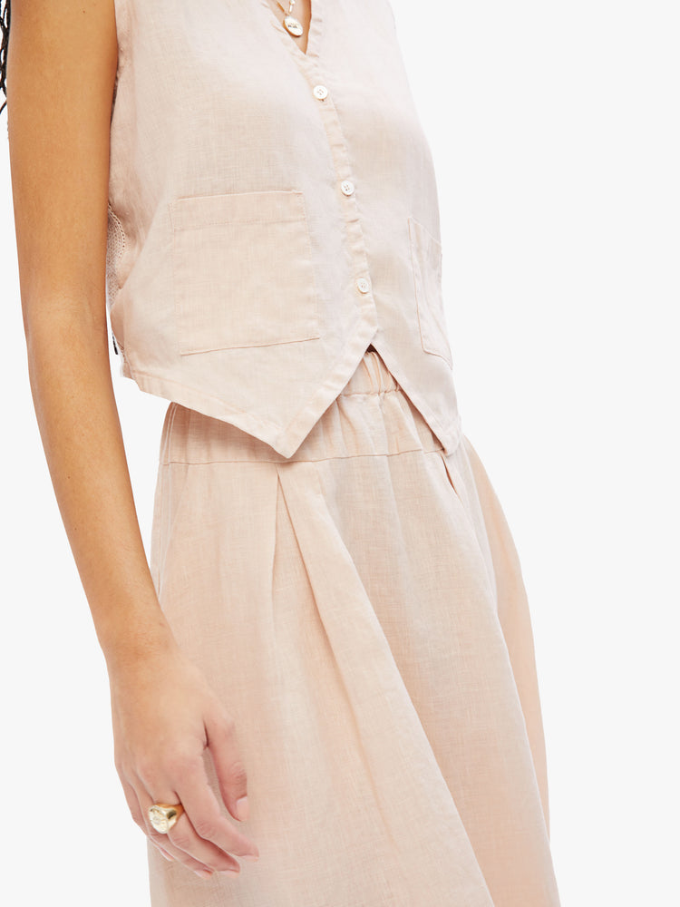 Close up waist line view of a woman in Elsa Esturgie a french brand handcrafted from 100% linen in an off-white hue, this midi skirt has a high rise waistband with soft pleats throughtout, side pockets and a floaty feel