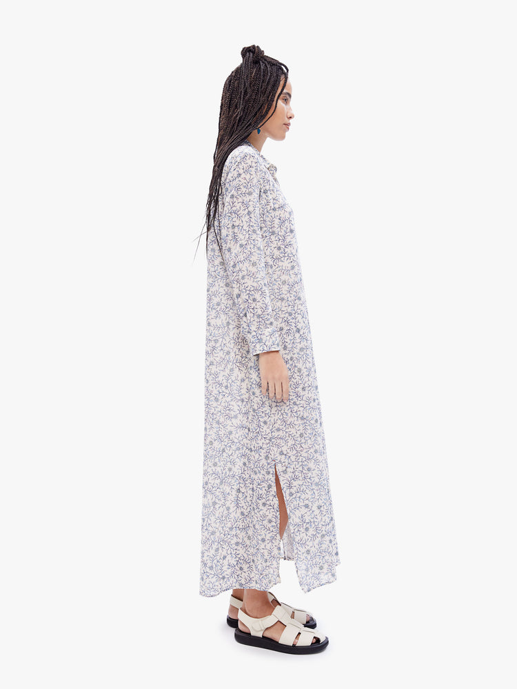 Side full body view of a woman in a maxi dress from XiRENA, the boden dress has a collared neck with buttons down the front, 3/4 length rolled sleeves and a loose calf length skirt with knee-high side slits in a delicate floral print