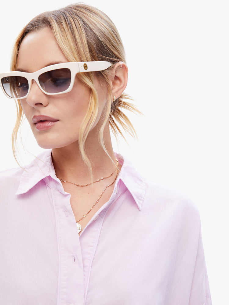 Close view of a woman in a light pink button down from XiRENA, the long sleeve shirt is light, airy with a loose fit, drop shoulders and a hip-grazing hem