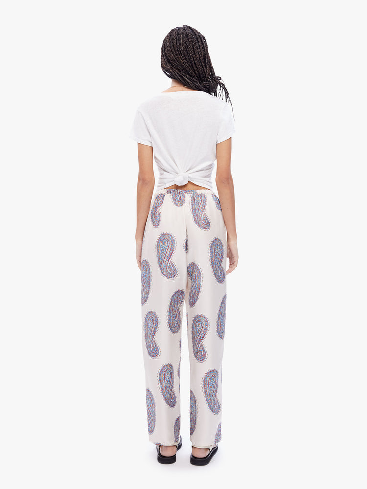 Back full body view of a woman in a high waisted pant from XiRena, pants are made from 100% silk in white with a paisley print and features a straight loose leg, side slit pockets and elastic waist