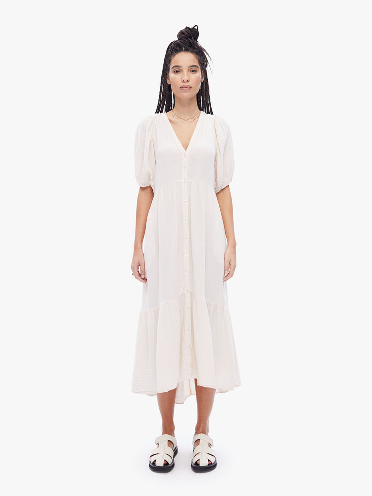 Front full body view of a woman in a maxi dress from XiRENA, the dress features a Vneck, short balloon sleeves and flowy tiered skirt in an off- white hue