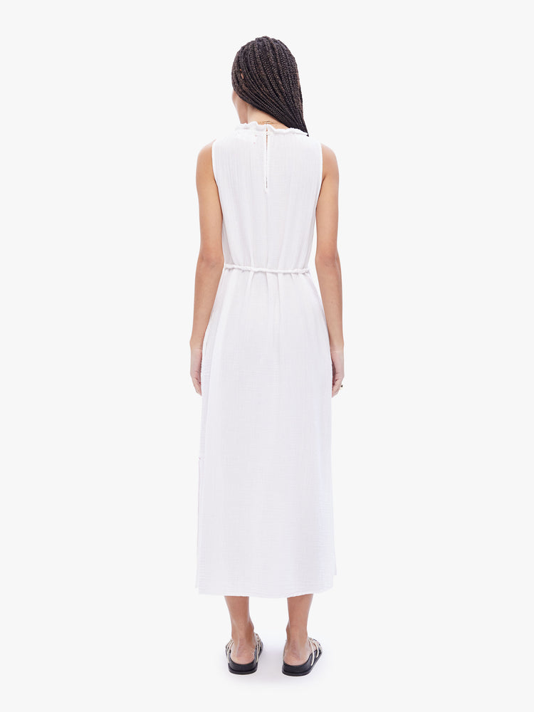 Back full body view of a woman in a sleeveless maxi dress from XiRENA, dress is made from 100% cotton in white and features a ruffled crewneck, tied waist, ankle length hem and effortless vibe