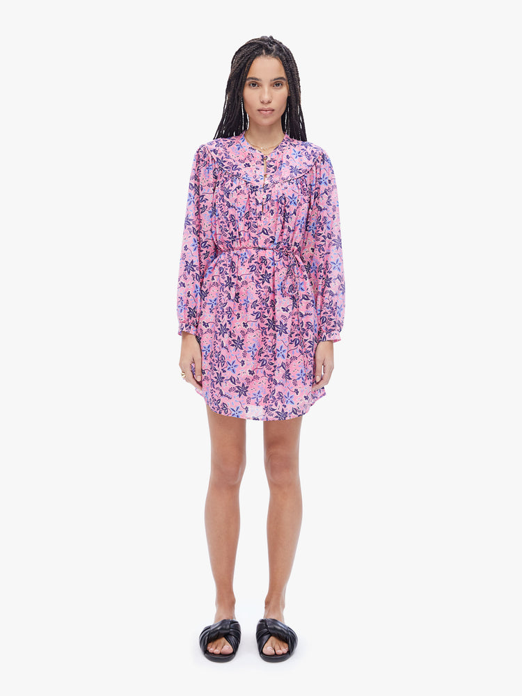 Front full body view of a woman in the Bellamy dress from XiRENA made from a blend of cotton and silk in a pink floral print, the mini dress is designed with a buttoned Vneck, long balloon sleeves, a tied waist, and a flowy skirt that hits mid-thigh