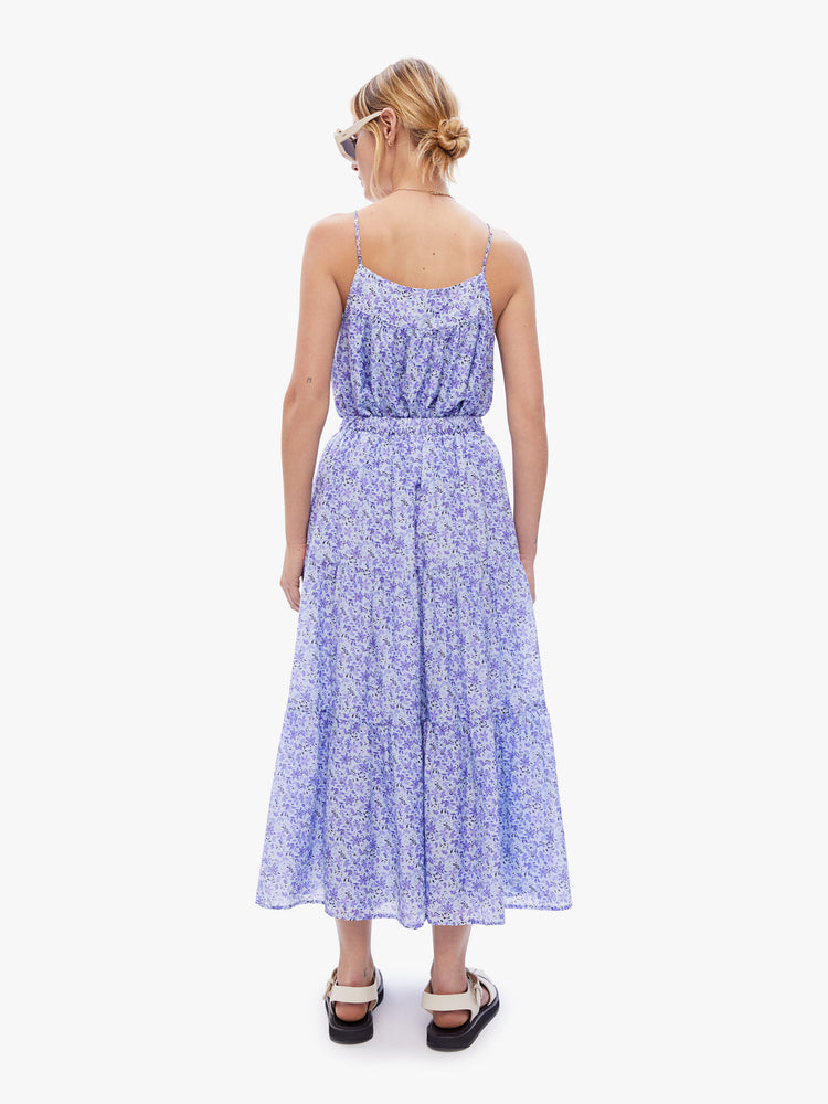Back full body view of a woman in a maxi skirt from XiRENA made from a blend of cotton and silk in a periwinkle floral print, skirt is designed with an elastic high waist, buttons down the front and a flowy gathered tiers