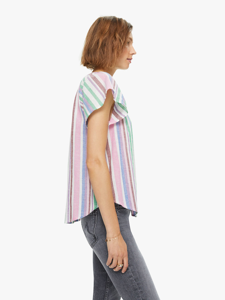 Side view of a woman in a 100% cotton in a baby pink, periwinkle and mint green stripe pattern, the Kimber top is designed with a buttoned V-neck, drop shoulders and a curved hem with side slits.