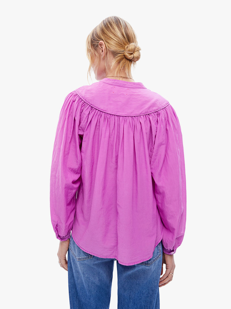 Back view of a woman in a casual blouse by XiRENA made from a blend of cotton and silk in a bright purple hue, the blouse is designed with long balloon sleeves and a buttoned vneck with ruffles throughout for a loose, flowy fit