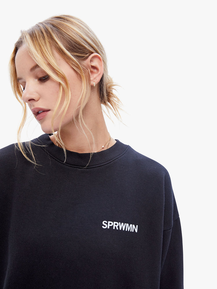 Front close up view of a womens black sweatshirt featuring a crew neck with dropped sleeves and "SPRWMN" printed on the chest.