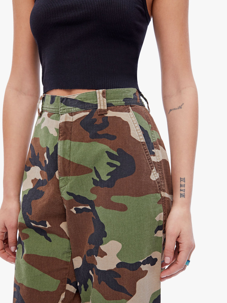 Side close up view of a womens high rise pant featuring a camo print, wide leg, and ankle length hem.