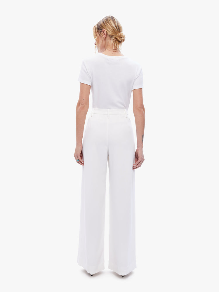 Back view of a woman in a white wide leg pant from SPRWMN with a high ride and a pleated waistband, a loose fit and full length inseam made from 100% cotton
