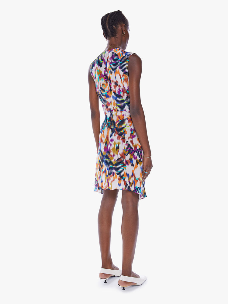 Back full body view of a woman in a sleeveless mini dress from Maria Cher, dress is designed in a blue, purple and orange print and features a V-neck, a pleated empire waist and a slim fit