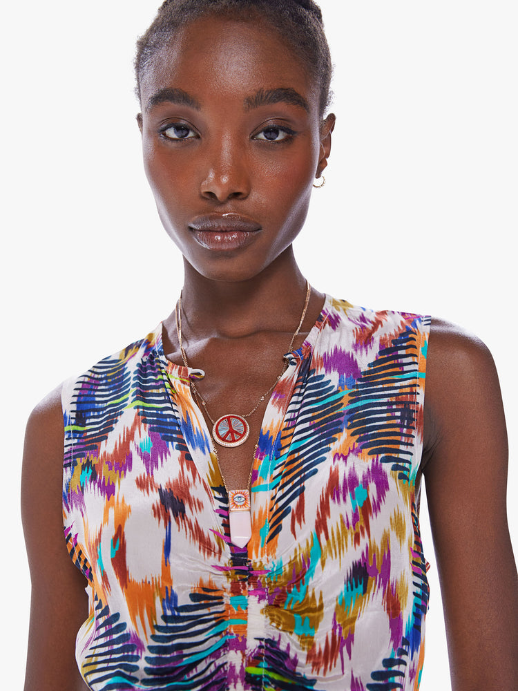 Close up view of a woman in a sleeveless mini dress from Maria Cher, dress is designed in a blue, purple and orange print and features a V-neck, a pleated empire waist and a slim fit