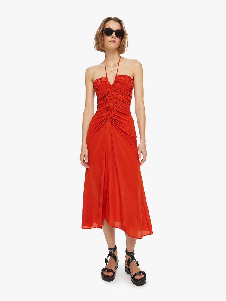 Front view a woman in a Maria Cher dress made from 100% silk in red, the Toribia midi dress features a halter neck, gathered bodice and a flowy skirt that hits mid-calf.