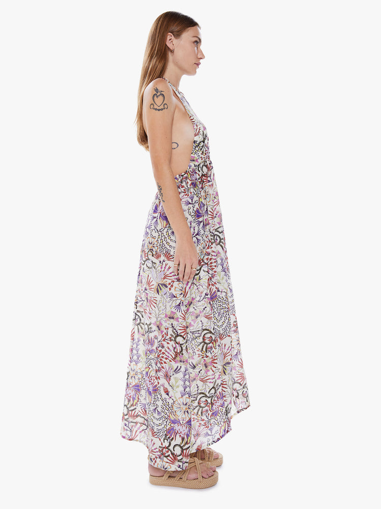 Side view of a woman in a sleeveless Maxi dress from Maria Cher a brand inspired by the founders hometown of Buenos Aires which reinterprets classic styles with bold prints and modern neutrals made from a blend of cotton and silk in a colorful abstract floral print and features a halter top with a deep Vneck, an empire waist and an ankle length skirt with flowy fit