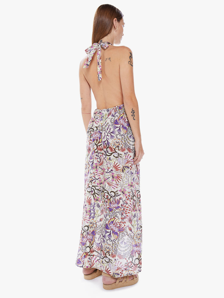 Back  view of a woman in a sleeveless Maxi dress from Maria Cher a brand inspired by the founders hometown of Buenos Aires which reinterprets classic styles with bold prints and modern neutrals made from a blend of cotton and silk in a colorful abstract floral print and features a halter top with a deep Vneck, an empire waist and an ankle length skirt with flowy fit
