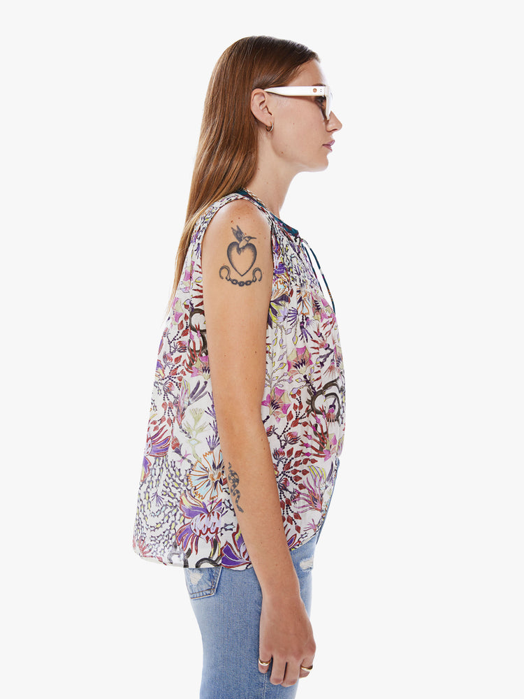 Side view of a woman in a Maria Cher blouse with bold prints and modern neutrals, made from a blend of cotton and silk in a colorful abstract floral print, the sleeveless blouse features a deep Vneck that laces and ties, a hip grazing hem and a loose, flowy fit