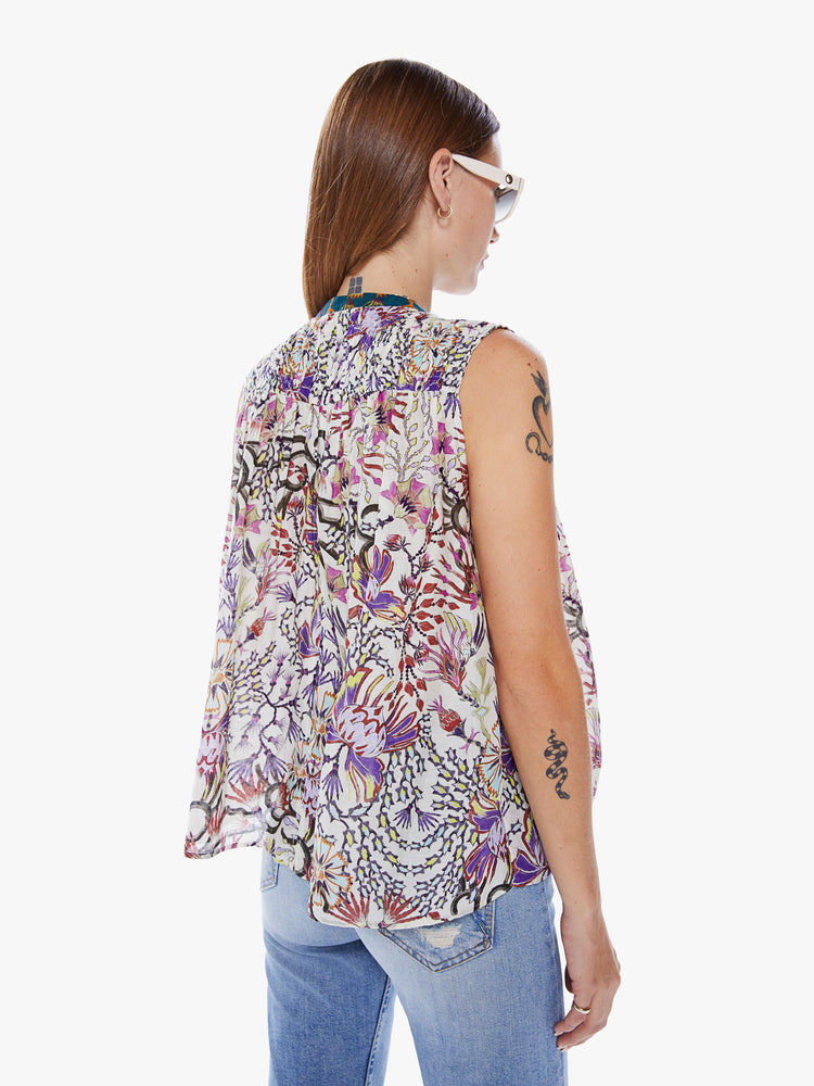 Back view of a woman in a Maria Cher blouse with bold prints and modern neutrals, made from a blend of cotton and silk in a colorful abstract floral print, the sleeveless blouse features a deep Vneck that laces and ties, a hip grazing hem and a loose, flowy fit
