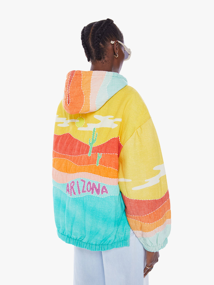 Back view of a woman in a colorful hoodie from Arizona Love, a french brand that combines a nomadic spirit with chic Parisian style, sweatshirt made from 100% cotton with yellow, orange and blue desert quilted graphic, features a drawstring hood, long sleeves with elastic hem an oversized front patch pocket and a boxy fit