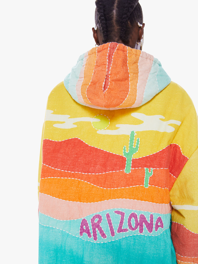 Back close up view of a woman in a colorful hoodie from Arizona Love, a french brand that combines a nomadic spirit with chic Parisian style, sweatshirt made from 100% cotton with yellow, orange and blue desert quilted graphic, features a drawstring hood, long sleeves with elastic hem an oversized front patch pocket and a boxy fit