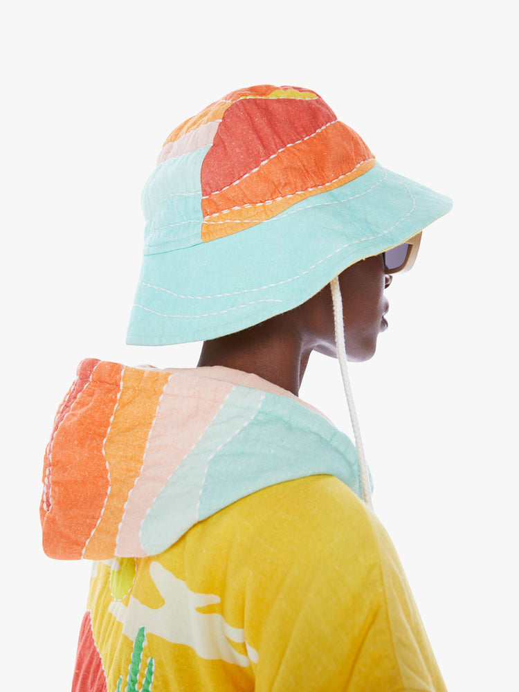 Back angle view of a woman in a wide-brim hat from Arizona Love, a french accessories brand that combines a nomadic spirit with chic Parisian style made from 100% cotton in a quilted pattern of orange, yellow and blue
