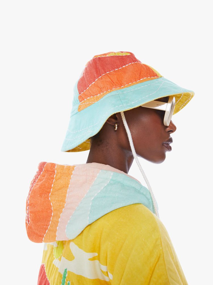 Side view of a woman in a wide-brim hat from Arizona Love, a french accessories brand that combines a nomadic spirit with chic Parisian style made from 100% cotton in a quilted pattern of orange, yellow and blue