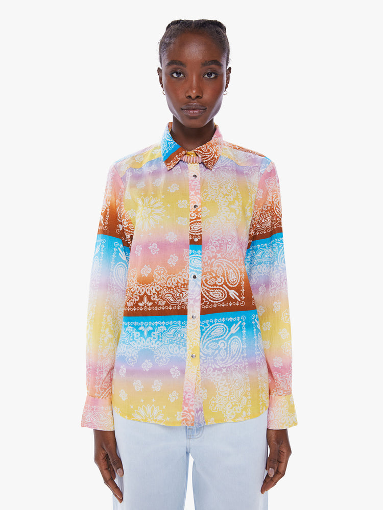 Front view of a woman in a handcrafted button up shirt from Arizona Love, a French brand that combines a nomadic spirit with chic Parisian style, the shirt is made from 100% cotton bandanas tie-dyed in pastel rainbow hues and features long sleeve, a curved hem and slightly loose fit 
