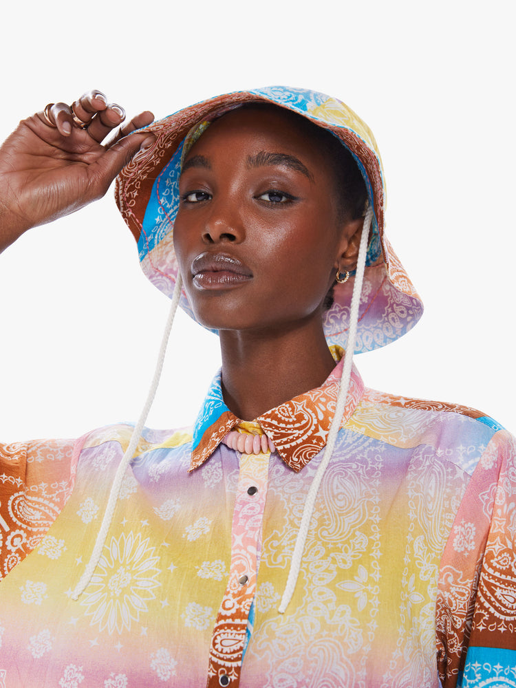 Front view of a woman in a wide-brim bucket hat from Arizona Love, a French accessories brand that combines a nomadic spirit with chic Parisian style made from 100% cotton bandanas tie-dyed in pastel rainbow hues