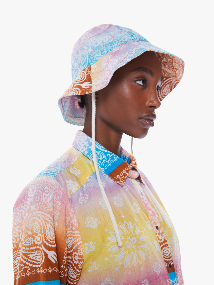 Side view of a woman in a wide-brim bucket hat from Arizona Love, a French accessories brand that combines a nomadic spirit with chic Parisian style made from 100% cotton bandanas tie-dyed in pastel rainbow hues