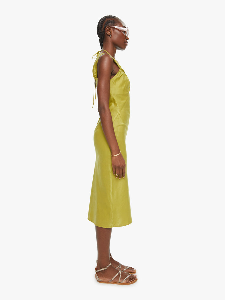 Side view of a woman a chartreuse hue dress, and features a gathered neckline, thick straps, a slim fit and midi-length hem.