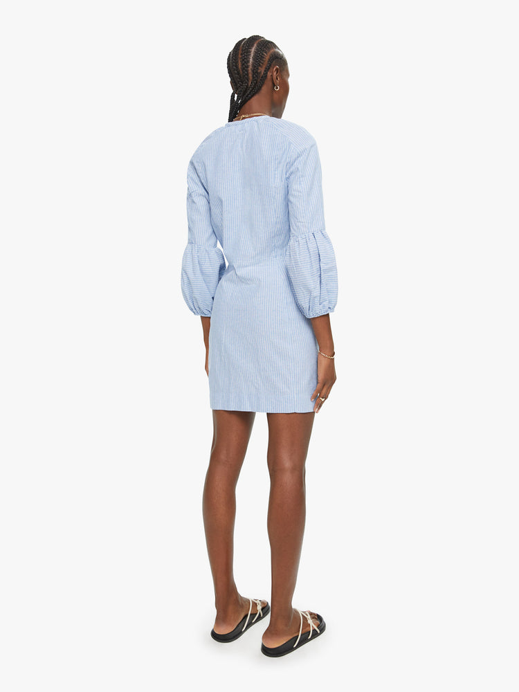 Back view of Vita dress features a buttoned V-neck, 3/4-length sleeves with gathered elastic hems, and a narrow fit. Made of 100% cotton in a light blue chambray with subtle white stripes, the slim-fitting dress is soft and lightweight.