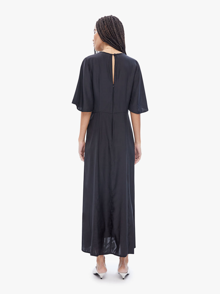 Back  full body view of a woman in maxi dress made from 100% silk in black, features a crewneck, flowy elbow-length sleeves, a gathered curved waist and an ankle length hem