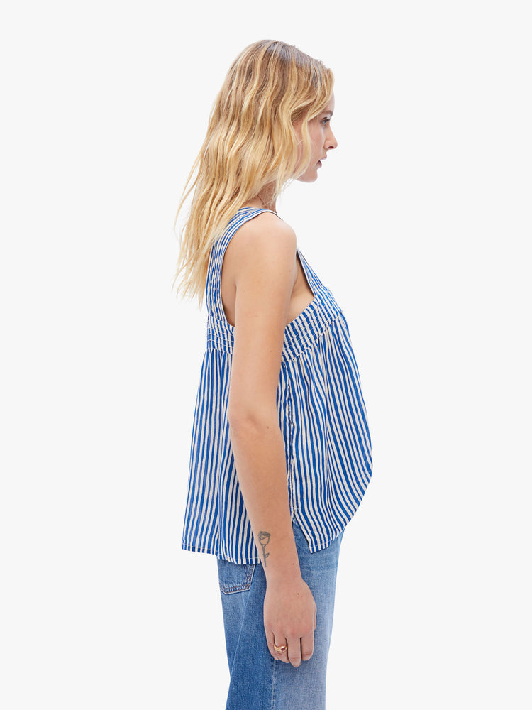 Side view of a womens sleeveless blouse featuring white and blue stripes and a flowy fit.