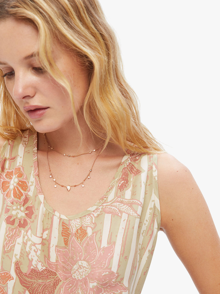 Close up view of woman hip-grazing hem and a loose, boxy fit tank in a tan stripe pattern with warm-toned sunflowers.