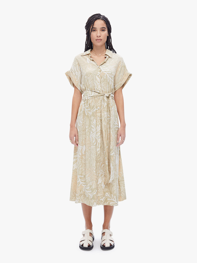 Front view of a woman collared V-neck, rolled short sleeves, a tied waist dress with flowy skirt that hits at mid-calf in a cream leaf print.
