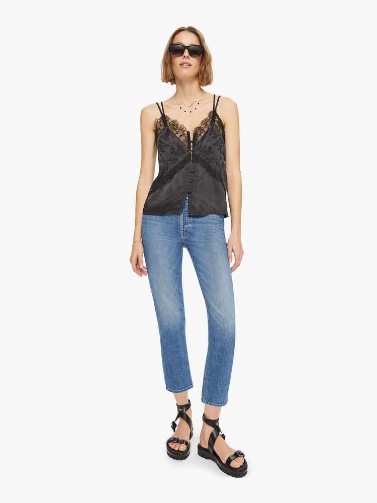 Full body view of a woman black lace top with V-neck , buttons down the front and spaghetti straps.