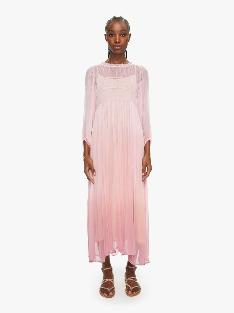 Front view of a woman baby pink ombre hue maxi dress with ruffled crewneck, cropped sleeves, gathered waist and uneven hem.