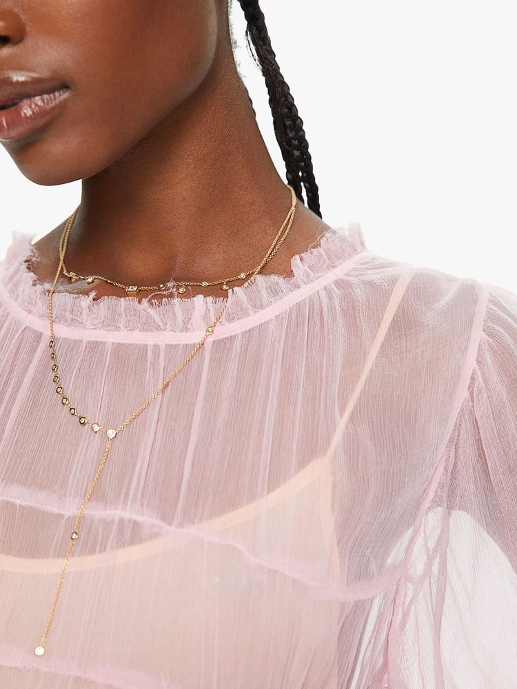 Close up view of a woman baby pink ombre hue maxi dress with ruffled crewneck, cropped sleeves, gathered waist and uneven hem.