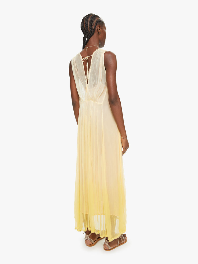 Back view of a woman yellow ombre hue maxi dress with Vneck and uneven hem.