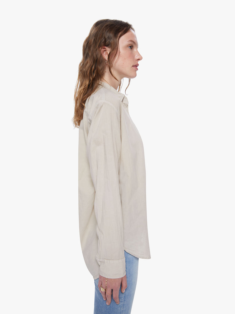 A side view of a woman wearing a tan button up shirt