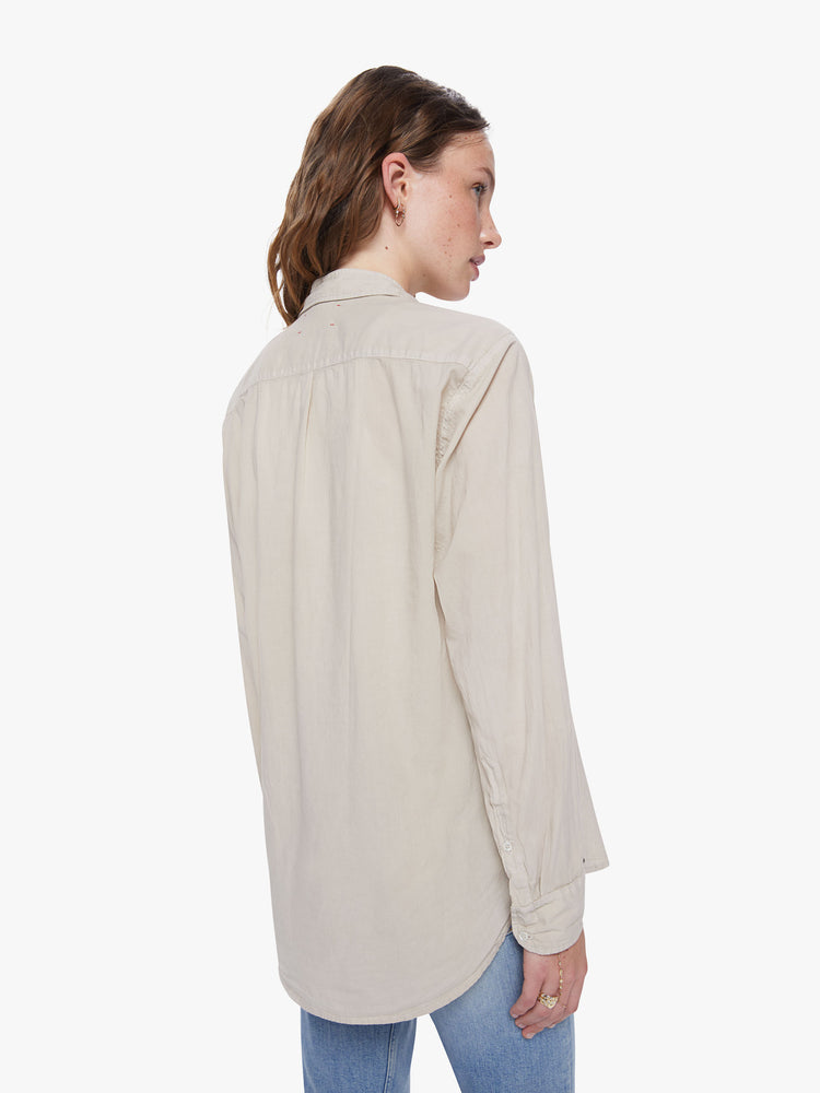A back view of a woman wearing a tan button up shirt