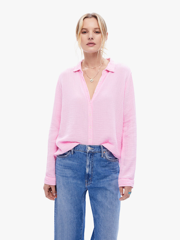 Front view of a woman in a baby pink button down from XiRena, the long sleeve shirt features a Vneck and curved hem with a light and airy fit