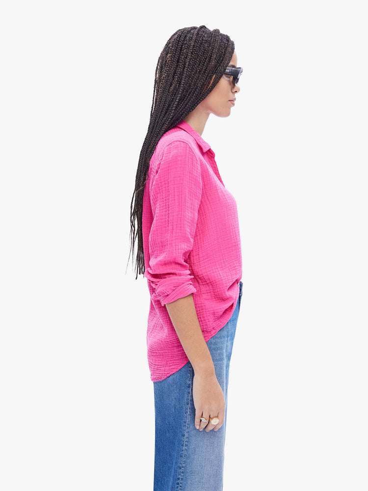 Side view of a woman in hot pink button down from XiRENA made from 100% cotton, the long sleeve shirt features a Vneck and curved hem with a light and airy fit