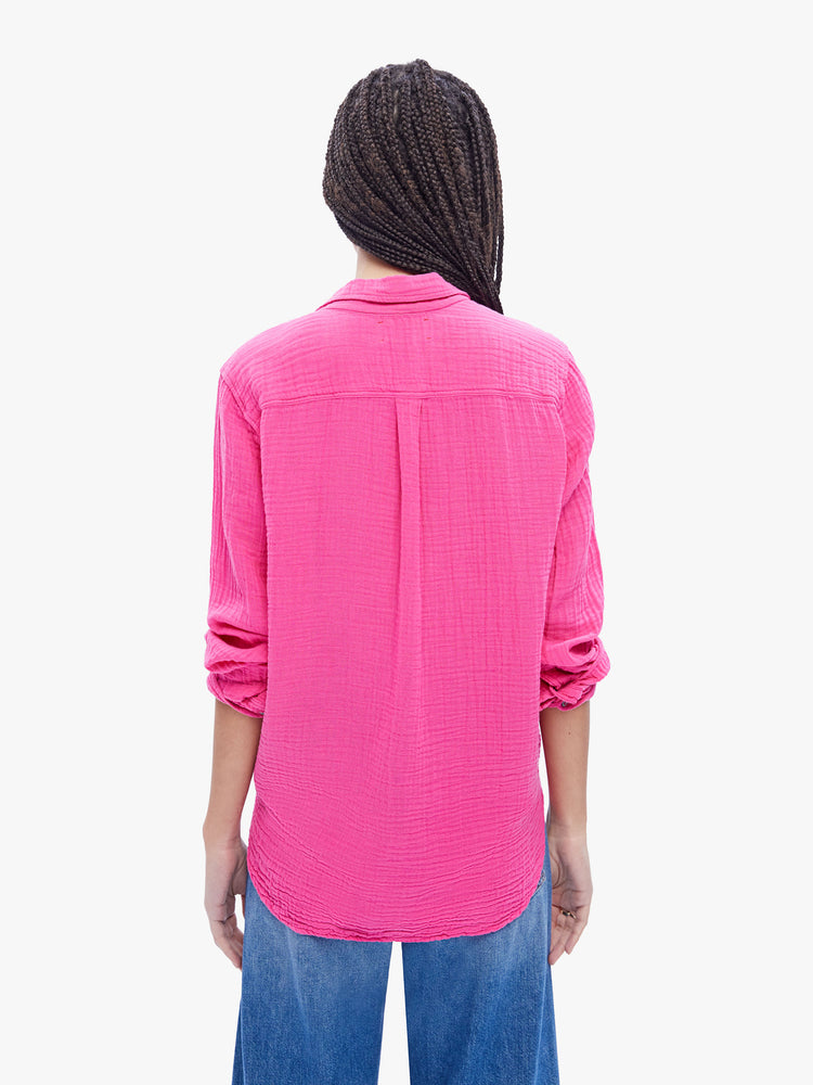 Back view of a woman in hot pink button down from XiRENA made from 100% cotton, the long sleeve shirt features a Vneck and curved hem with a light and airy fit