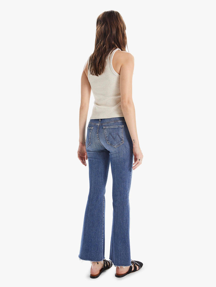 Back view of women's mid rise medium blue flare with frayed hem