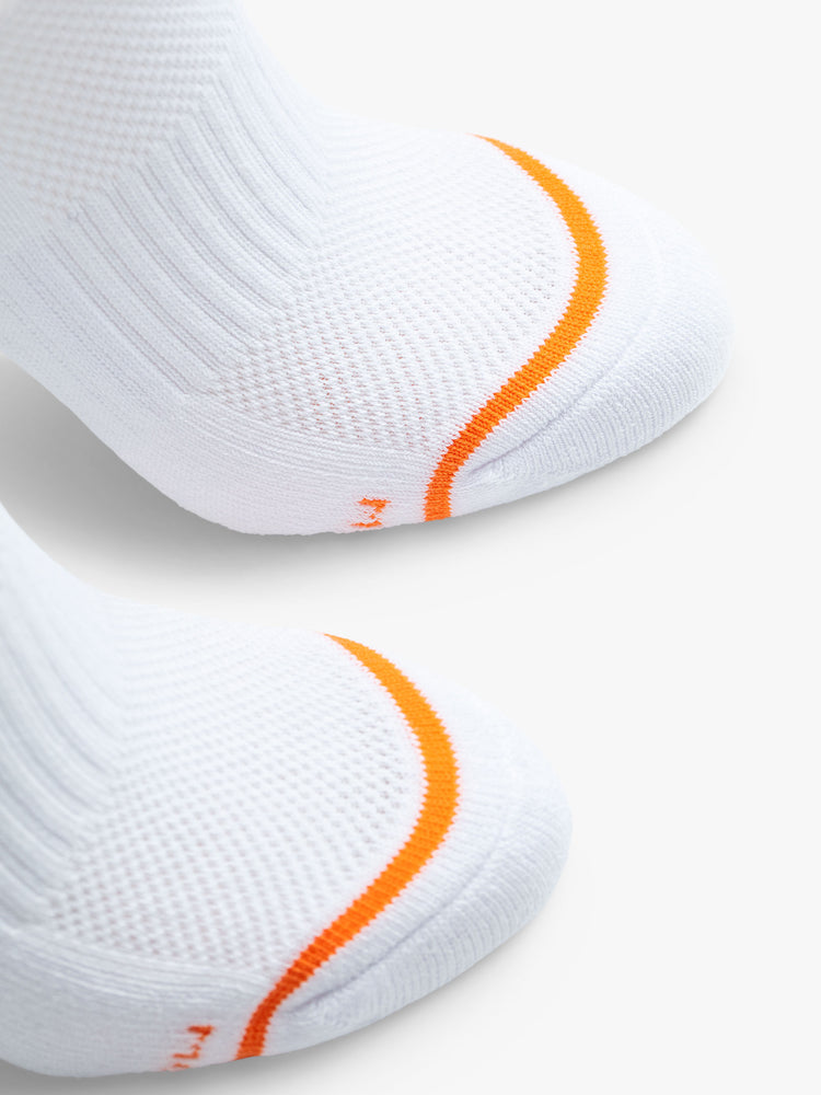 Close up detail view of the toes of a pair of white socks featuring an orange stripe across the toe.